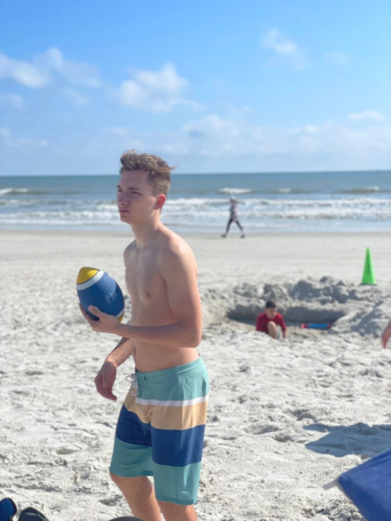 Teenage Boy Playing Football on Beach