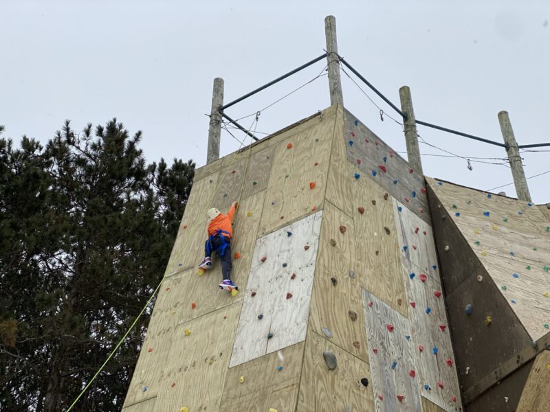 orange shirt at top of rock wall