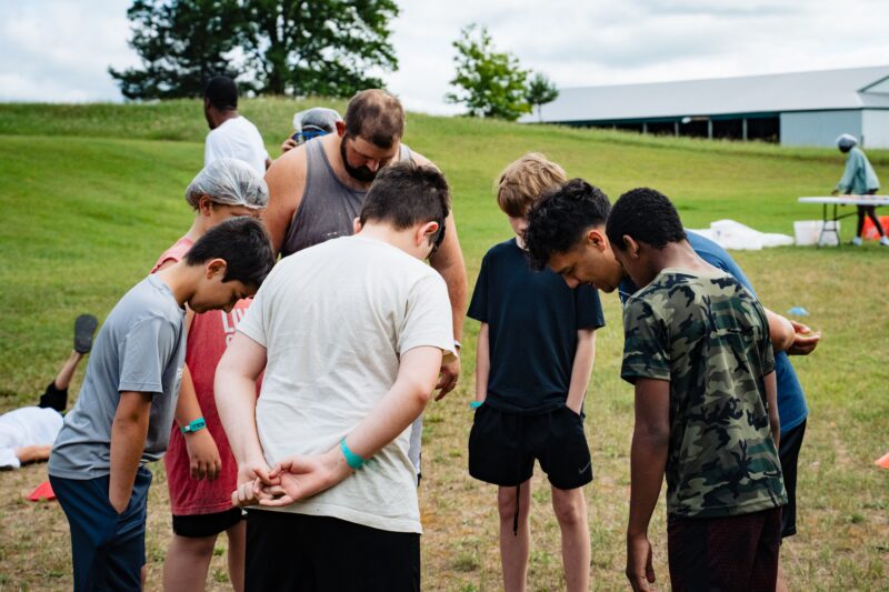 teen guys praying at camp